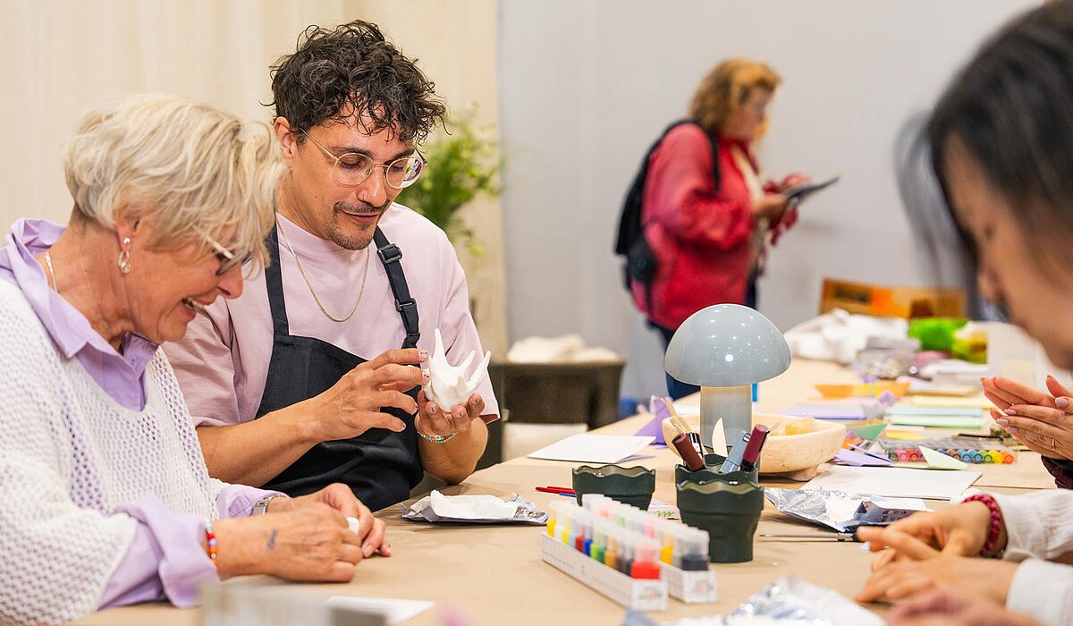 zwei Menschen an einem Tisch arbeiten mit Knete